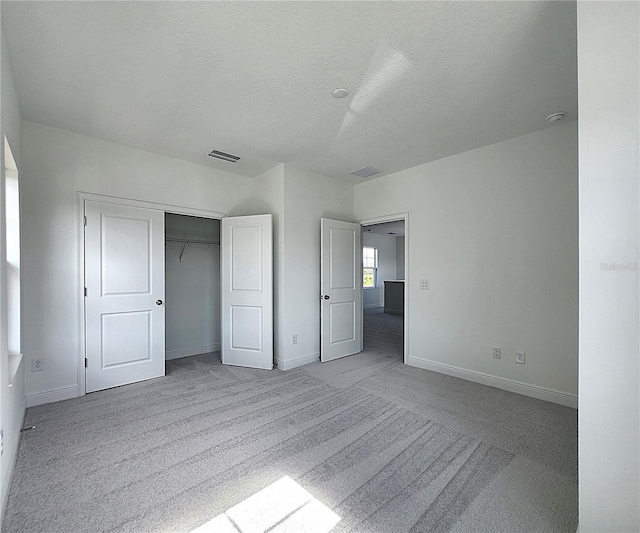 unfurnished bedroom featuring a closet, a textured ceiling, and light carpet