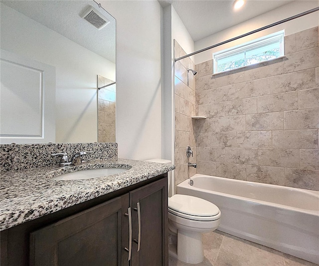 full bathroom with tiled shower / bath, a textured ceiling, vanity, tile patterned floors, and toilet