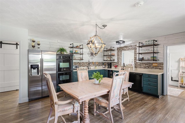 dining room with a barn door, dark hardwood / wood-style floors, wood walls, and a chandelier