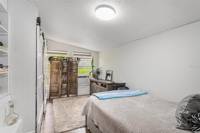 bedroom with light hardwood / wood-style floors, a textured ceiling, and vaulted ceiling