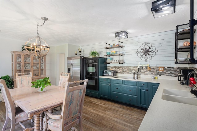 kitchen with sink, stainless steel fridge with ice dispenser, blue cabinetry, dark hardwood / wood-style floors, and decorative light fixtures