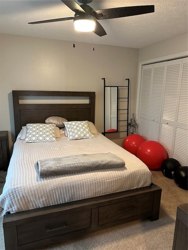 bedroom with ceiling fan, a closet, light colored carpet, and a textured ceiling