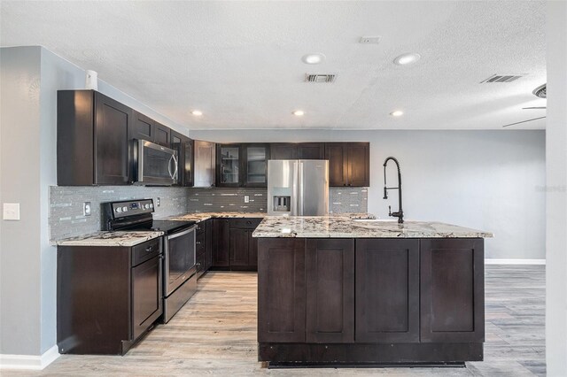 kitchen featuring a center island with sink, light wood-type flooring, and appliances with stainless steel finishes