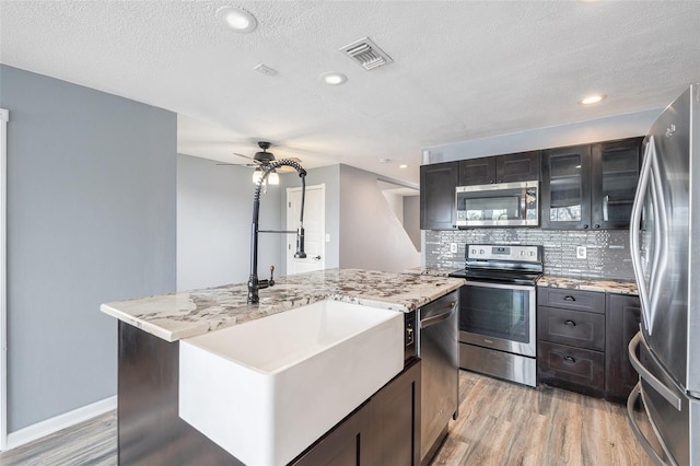 kitchen featuring a kitchen island, stainless steel appliances, a textured ceiling, and light hardwood / wood-style floors