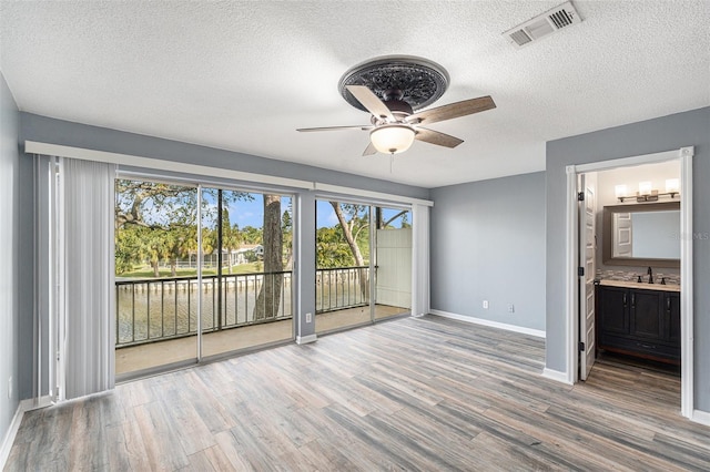 unfurnished room featuring ceiling fan, hardwood / wood-style flooring, and a textured ceiling