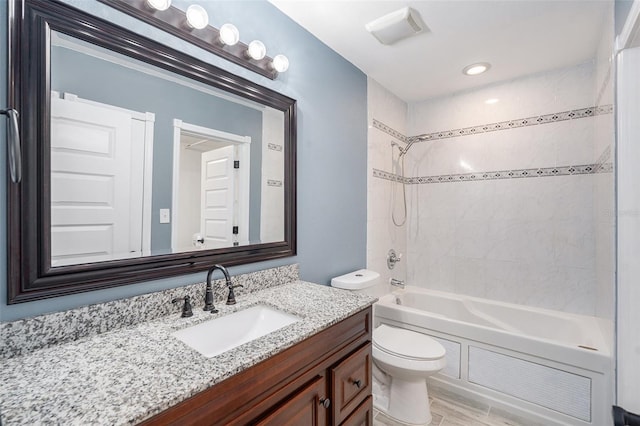 full bathroom featuring vanity, hardwood / wood-style floors, tiled shower / bath combo, and toilet