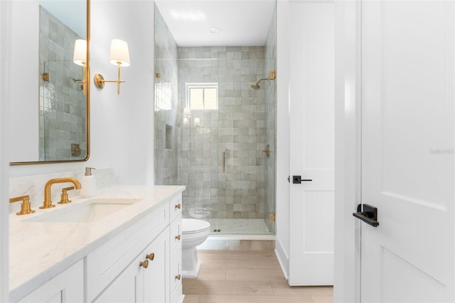 bathroom featuring walk in shower, wood-type flooring, toilet, and vanity