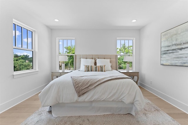 bedroom with light hardwood / wood-style floors and multiple windows