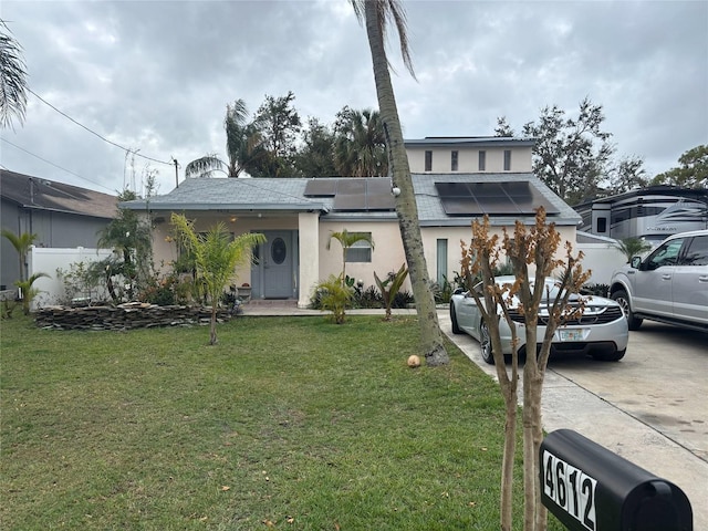 view of front of house featuring solar panels and a front lawn