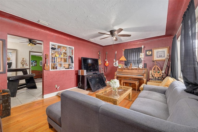 living room with ceiling fan, wood-type flooring, and a textured ceiling