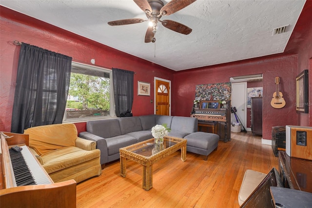 living room featuring wood-type flooring, ceiling fan, and a textured ceiling