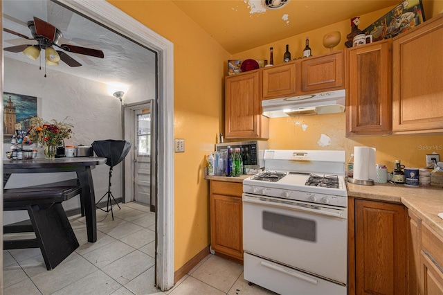 kitchen with light tile patterned flooring, ceiling fan, lofted ceiling, and white gas range oven