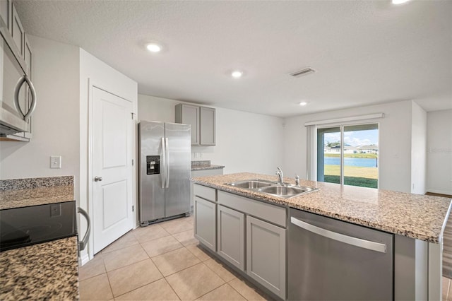 kitchen with stainless steel appliances, a textured ceiling, sink, an island with sink, and gray cabinets