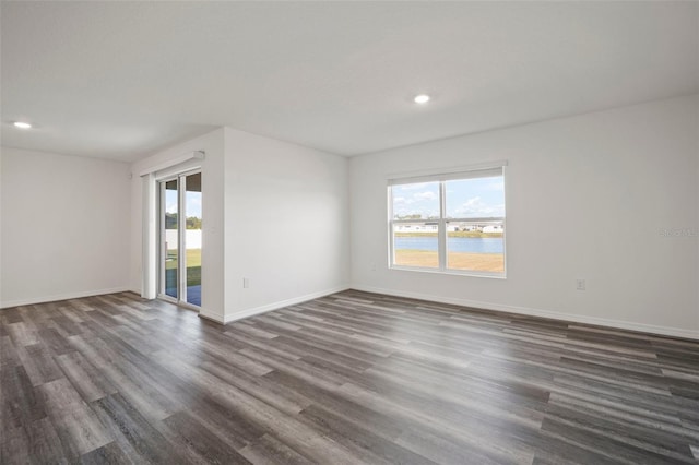 spare room with a water view and dark hardwood / wood-style floors