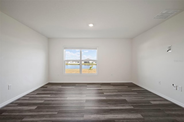 empty room featuring dark hardwood / wood-style flooring and a water view