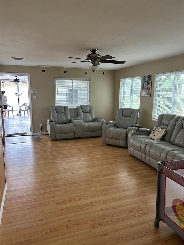 living room with light wood-type flooring, a wealth of natural light, and ceiling fan