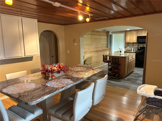 dining room featuring light hardwood / wood-style flooring, wood walls, and wood ceiling