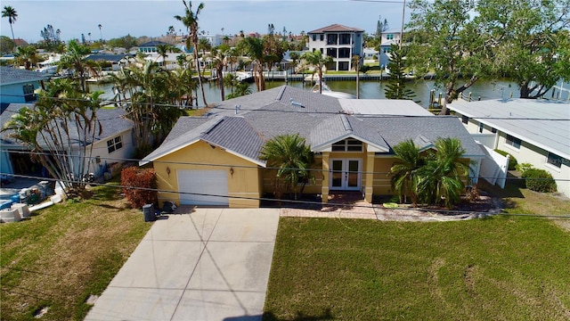 view of front of home featuring a water view, a residential view, a front yard, french doors, and a garage