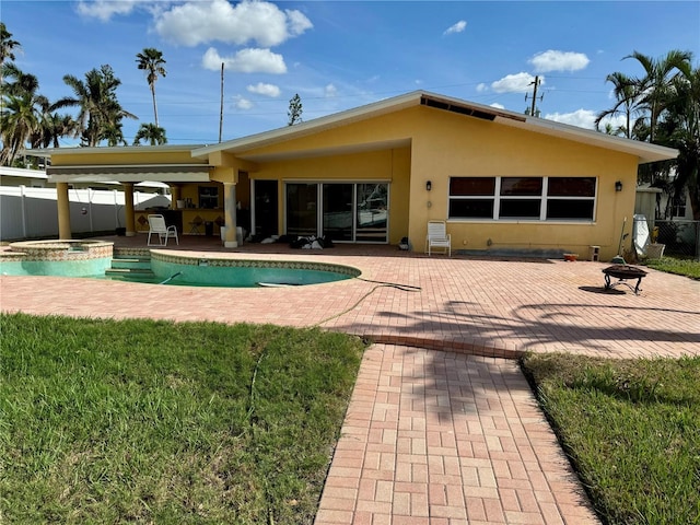 rear view of house featuring a patio area, a lawn, and a swimming pool with hot tub