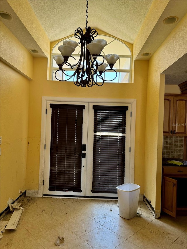 foyer entrance featuring a notable chandelier, a textured ceiling, and lofted ceiling