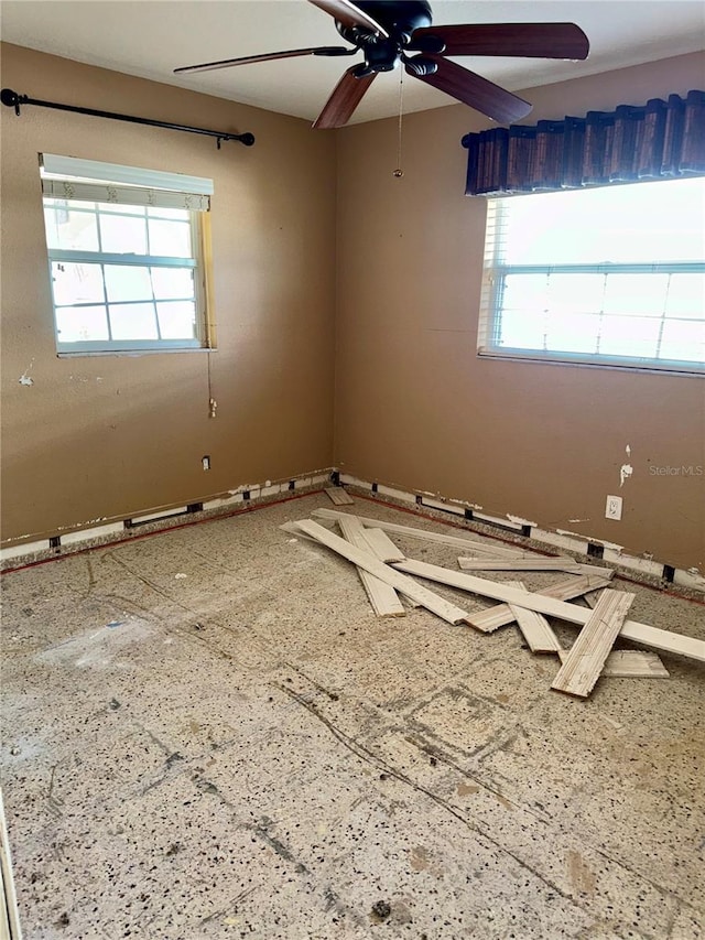 unfurnished room featuring a healthy amount of sunlight and ceiling fan