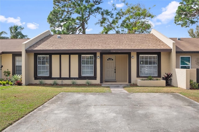 ranch-style home featuring stucco siding, a shingled roof, and a front yard