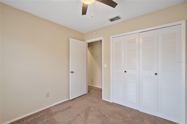 unfurnished bedroom with ceiling fan, light carpet, and a closet