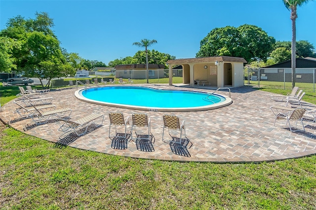 view of pool with a lawn and a patio