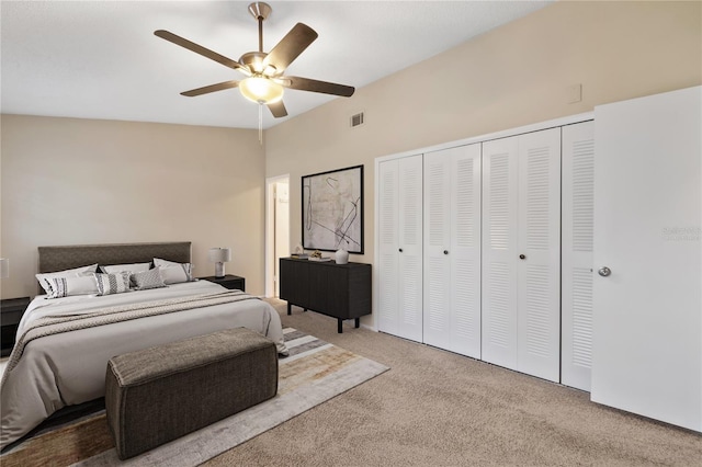 bedroom with visible vents, lofted ceiling, ceiling fan, carpet, and a closet