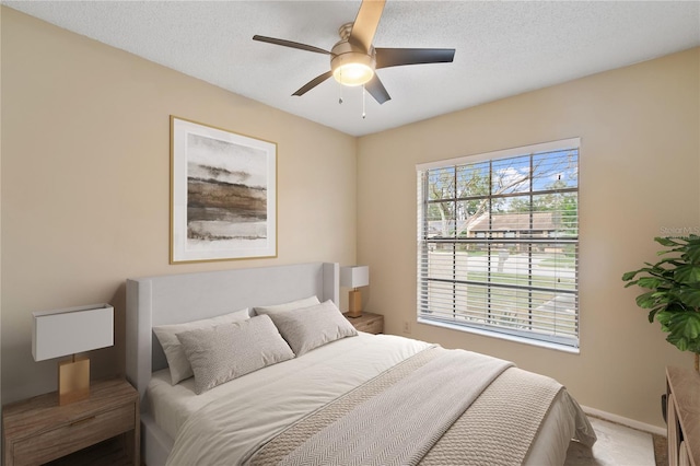 bedroom featuring a ceiling fan, carpet flooring, a textured ceiling, and baseboards