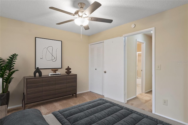 carpeted bedroom with a textured ceiling, ceiling fan, a closet, and baseboards