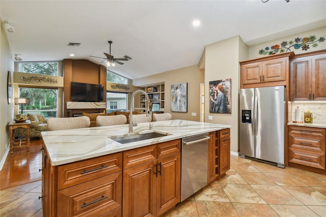 kitchen with a center island with sink, vaulted ceiling, sink, ceiling fan, and appliances with stainless steel finishes