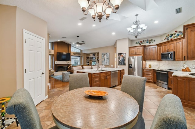 tiled dining area with sink, vaulted ceiling, and ceiling fan with notable chandelier