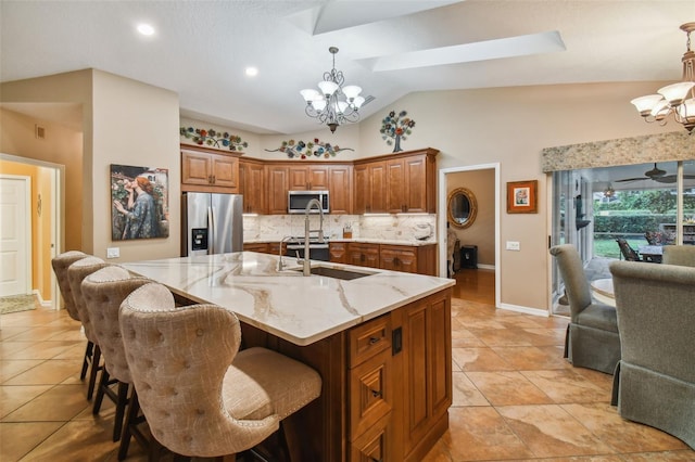 kitchen featuring a large island with sink, appliances with stainless steel finishes, a kitchen breakfast bar, vaulted ceiling with skylight, and decorative light fixtures