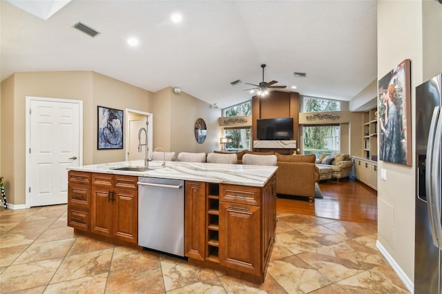 kitchen featuring appliances with stainless steel finishes, sink, vaulted ceiling, ceiling fan, and a kitchen island with sink