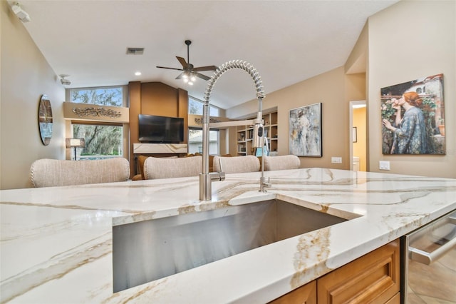 kitchen featuring tile patterned flooring, light stone counters, ceiling fan, lofted ceiling, and dishwasher