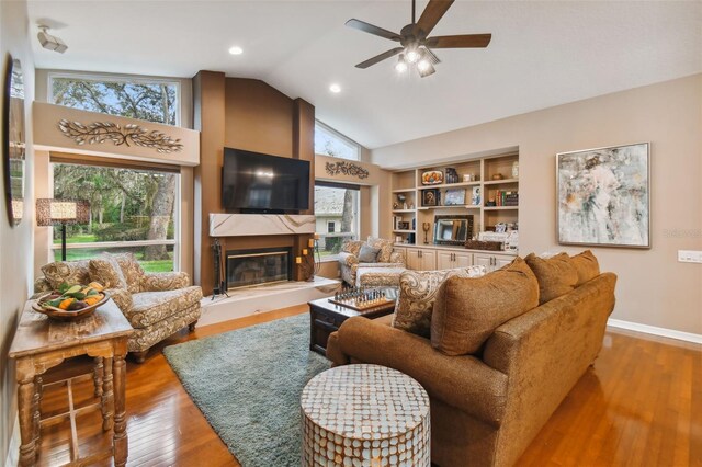 living room featuring high vaulted ceiling, ceiling fan, hardwood / wood-style floors, and a large fireplace