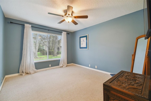 carpeted spare room with a textured ceiling and ceiling fan