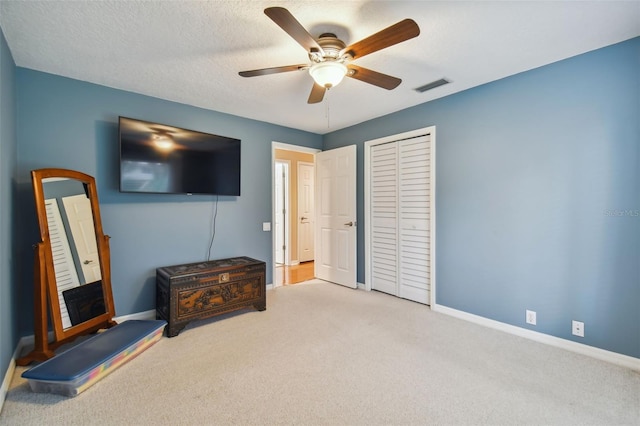 carpeted bedroom with a closet, a textured ceiling, and ceiling fan