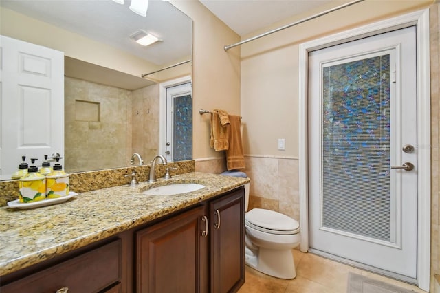 bathroom featuring tile walls, vanity, toilet, and tile patterned flooring