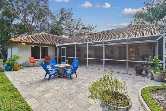 rear view of property with glass enclosure, a patio area, and a sunroom