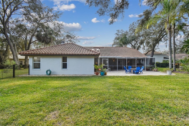 rear view of house featuring a lawn, a sunroom, and a patio area