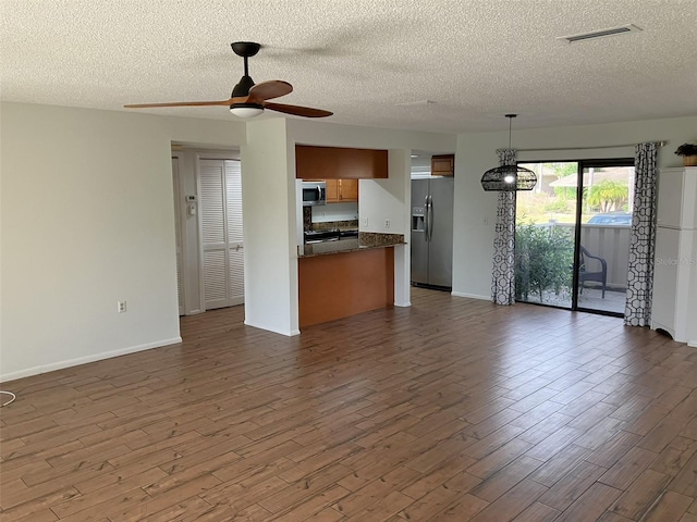 unfurnished living room with ceiling fan, dark wood-type flooring, and a textured ceiling