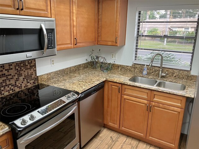 kitchen featuring light stone countertops, stainless steel appliances, and sink