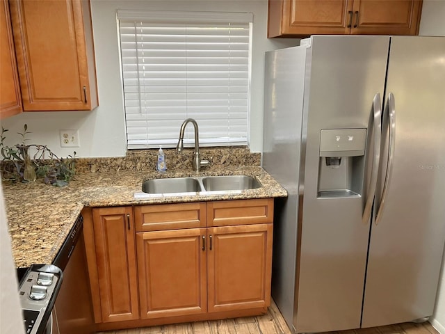 kitchen with stainless steel appliances, light stone counters, and sink