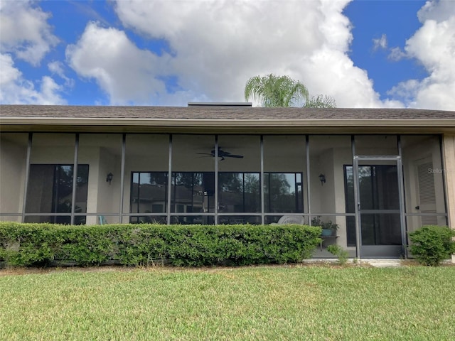 rear view of property featuring a yard and ceiling fan