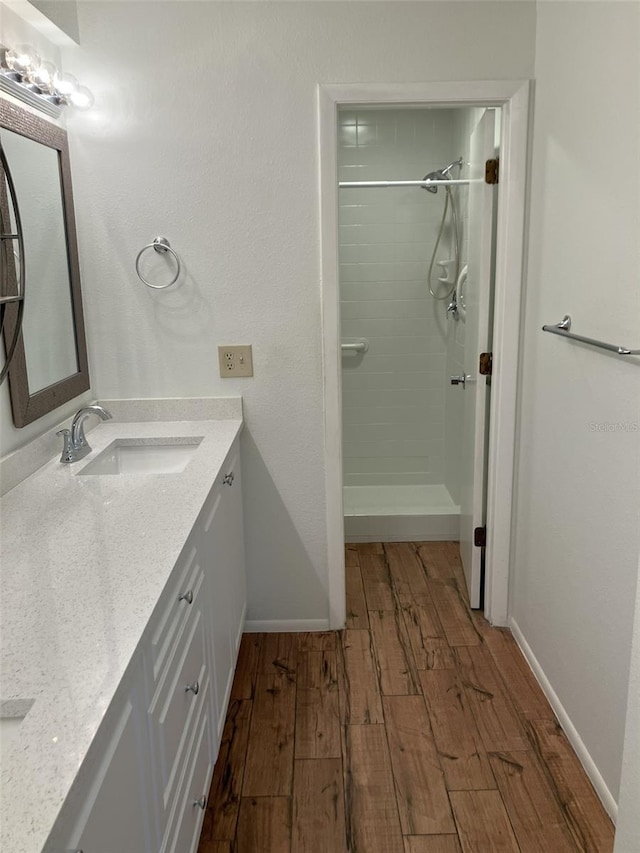 bathroom featuring hardwood / wood-style floors, vanity, and a tile shower