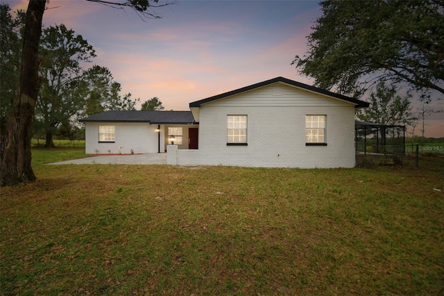 back house at dusk featuring a yard and a patio area