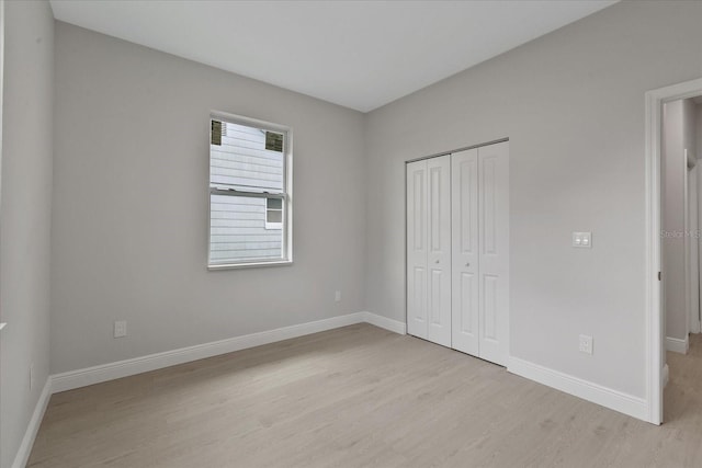 unfurnished bedroom with light wood-type flooring and a closet