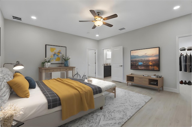 bedroom with connected bathroom, a closet, light hardwood / wood-style floors, and ceiling fan